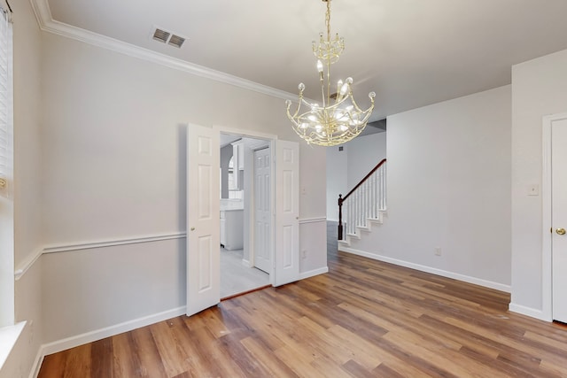 spare room with ornamental molding, hardwood / wood-style flooring, and a notable chandelier