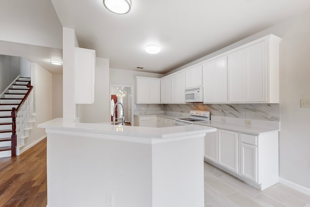 kitchen with white cabinetry, kitchen peninsula, decorative backsplash, white appliances, and sink