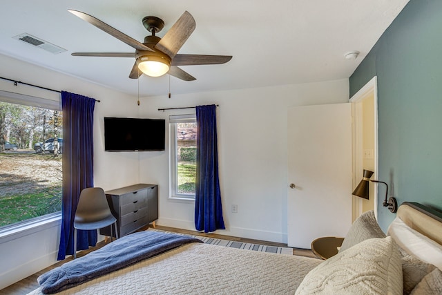 bedroom with multiple windows, ceiling fan, and light hardwood / wood-style flooring