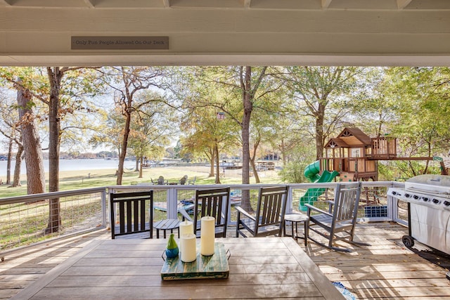 wooden deck featuring a water view and a playground