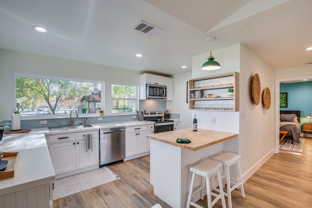 kitchen featuring butcher block counters, white cabinets, pendant lighting, and appliances with stainless steel finishes