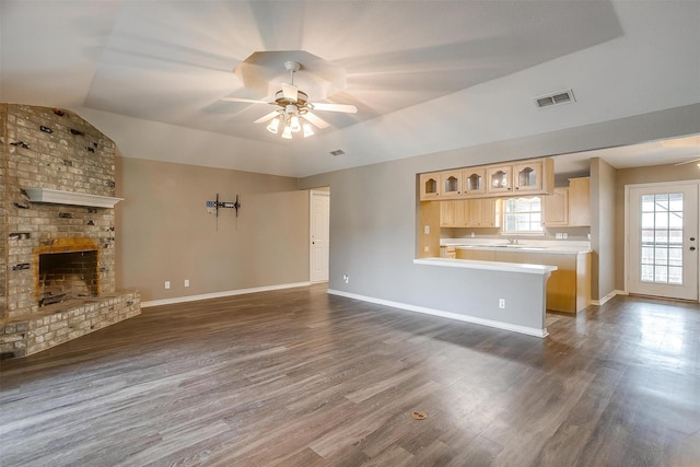 unfurnished living room featuring lofted ceiling, a fireplace, dark wood-type flooring, and ceiling fan