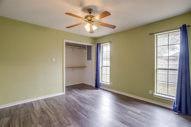 unfurnished bedroom with electric panel, ceiling fan, a closet, and hardwood / wood-style floors