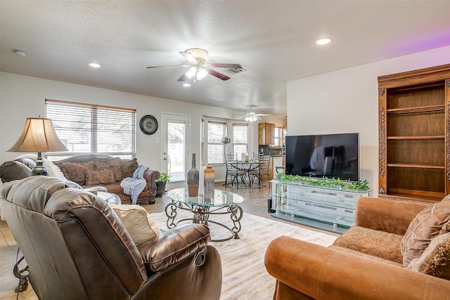 living room with a textured ceiling and ceiling fan