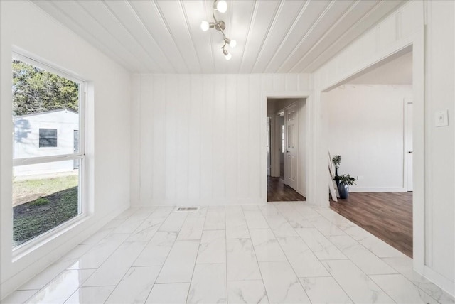 empty room with a notable chandelier, wooden ceiling, and plenty of natural light