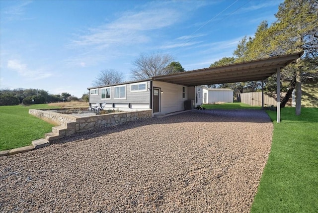 view of front facade with a front lawn, cooling unit, a carport, and a storage shed