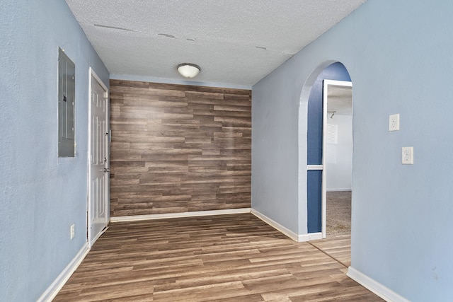 spare room featuring electric panel, a textured ceiling, and hardwood / wood-style floors