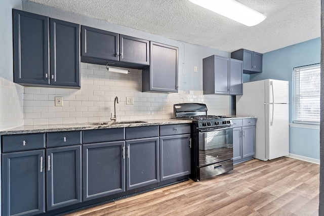 kitchen featuring sink, a textured ceiling, white fridge, and black gas stove