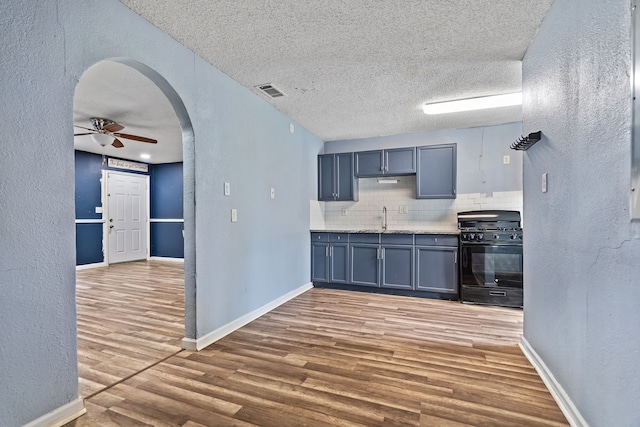 kitchen featuring black gas range, a textured ceiling, ceiling fan, decorative backsplash, and sink