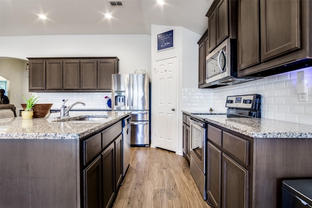 kitchen featuring sink, light hardwood / wood-style floors, light stone countertops, dark brown cabinetry, and appliances with stainless steel finishes