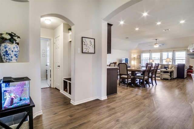 interior space featuring dark wood-style floors, arched walkways, recessed lighting, vaulted ceiling, and baseboards