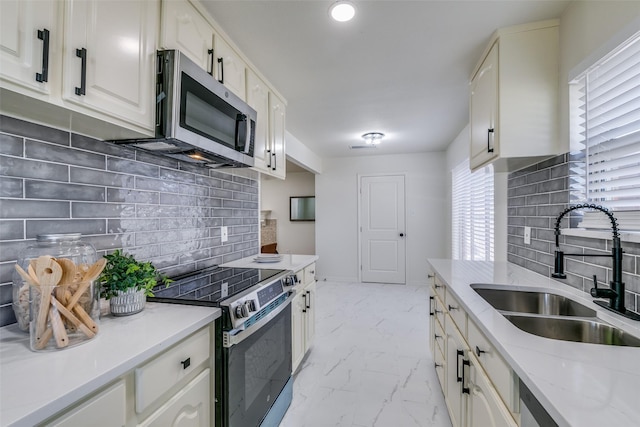 kitchen featuring appliances with stainless steel finishes, sink, light stone counters, and decorative backsplash