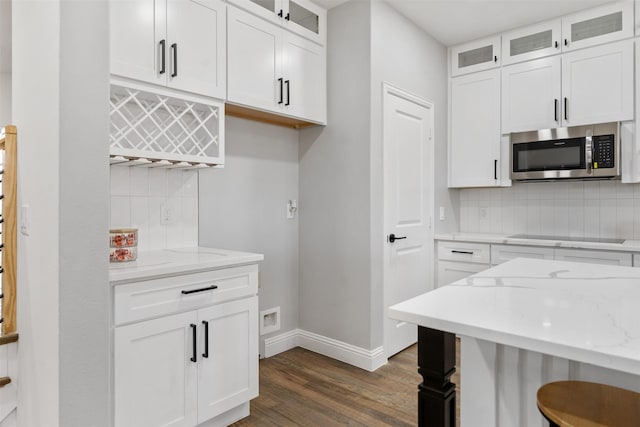 kitchen with white cabinets, backsplash, black electric cooktop, and light stone countertops