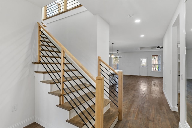 stairway featuring hardwood / wood-style floors and ceiling fan with notable chandelier