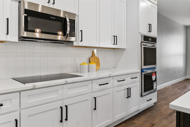 kitchen featuring white cabinets, light stone counters, tasteful backsplash, dark hardwood / wood-style flooring, and appliances with stainless steel finishes