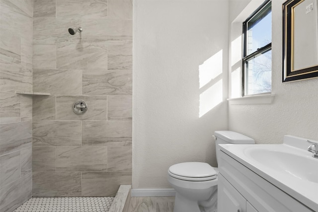 bathroom with vanity, tiled shower, and toilet