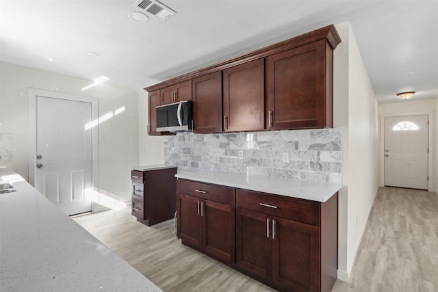 kitchen with light hardwood / wood-style flooring, dark brown cabinets, and tasteful backsplash