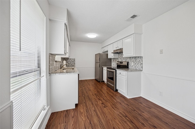 kitchen featuring white cabinetry, stainless steel appliances, light stone countertops, and dark wood-type flooring