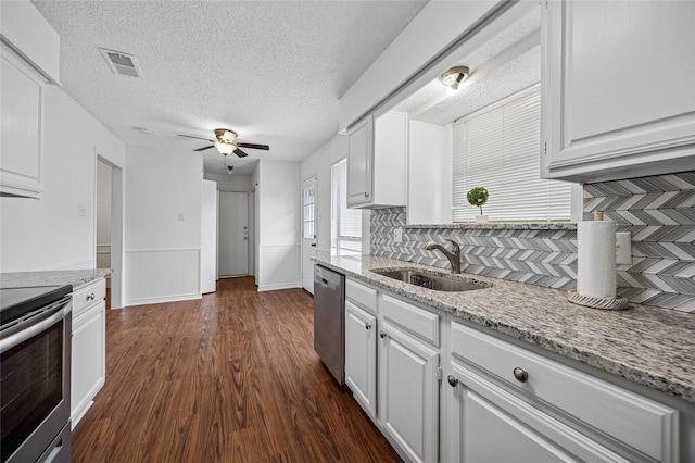 kitchen featuring sink, white cabinetry, light stone counters, dark hardwood / wood-style floors, and stainless steel appliances