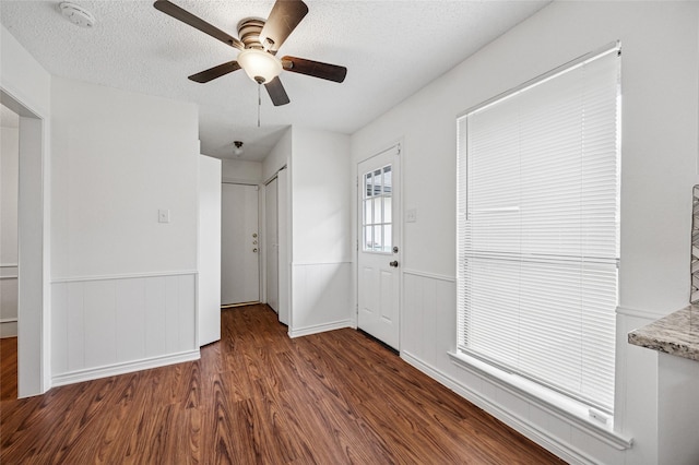 interior space with ceiling fan, dark wood-type flooring, and a textured ceiling