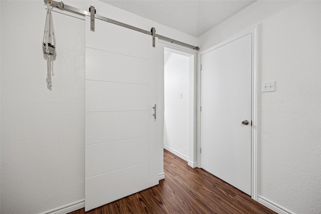 interior space featuring dark hardwood / wood-style floors, a barn door, and a textured ceiling