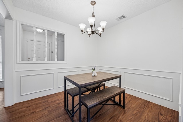 dining space with dark wood-type flooring, a chandelier, and a textured ceiling