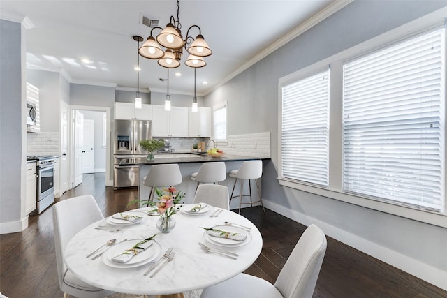 dining area featuring dark wood-type flooring, ornamental molding, sink, and a notable chandelier