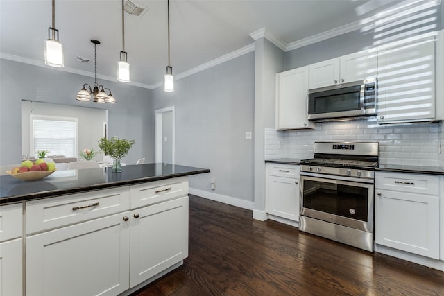 kitchen featuring appliances with stainless steel finishes, pendant lighting, tasteful backsplash, white cabinetry, and dark hardwood / wood-style flooring