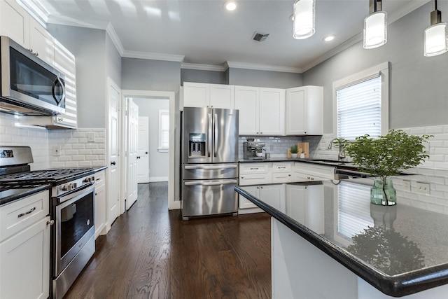 kitchen featuring sink, dark wood-type flooring, appliances with stainless steel finishes, white cabinetry, and decorative light fixtures