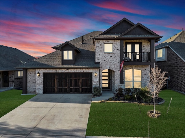 view of front of home featuring a yard, a balcony, and a garage