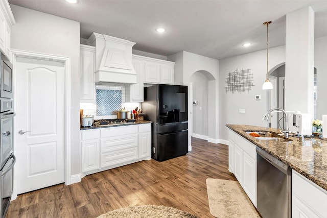 kitchen with custom exhaust hood, white cabinets, stainless steel appliances, hanging light fixtures, and sink