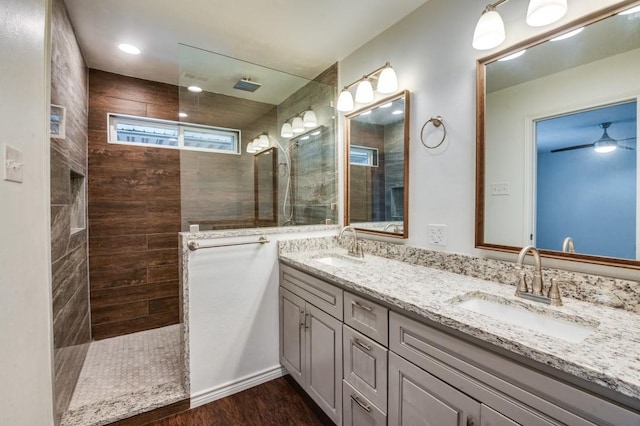 bathroom with ceiling fan, tiled shower, vanity, and hardwood / wood-style flooring