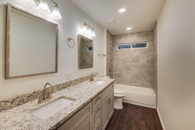 full bathroom with toilet, hardwood / wood-style flooring, tiled shower / bath combo, and vanity