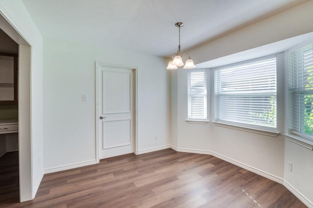 unfurnished dining area featuring a notable chandelier and hardwood / wood-style flooring