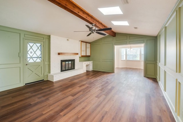 unfurnished living room with ceiling fan, vaulted ceiling with beams, a fireplace, and hardwood / wood-style flooring