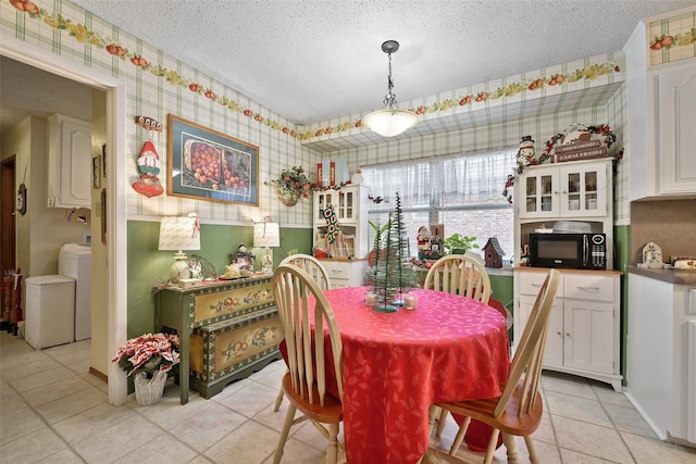 dining space featuring washer / clothes dryer, a textured ceiling, and light tile patterned floors