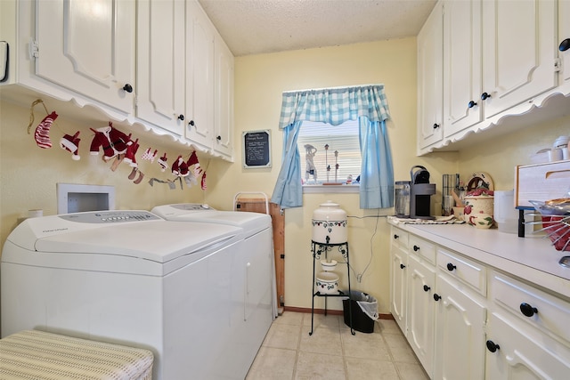 clothes washing area with a textured ceiling, washing machine and dryer, light tile patterned flooring, and cabinets