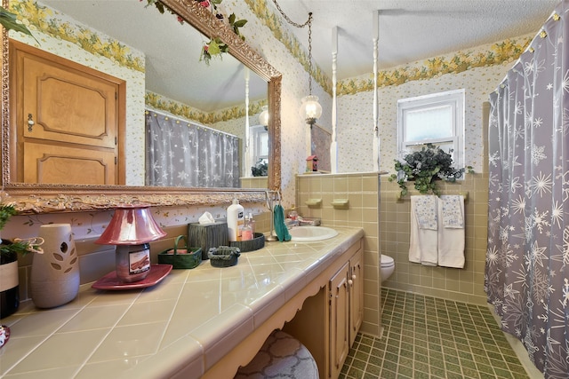 bathroom with toilet, vanity, a shower with curtain, tile patterned floors, and a textured ceiling