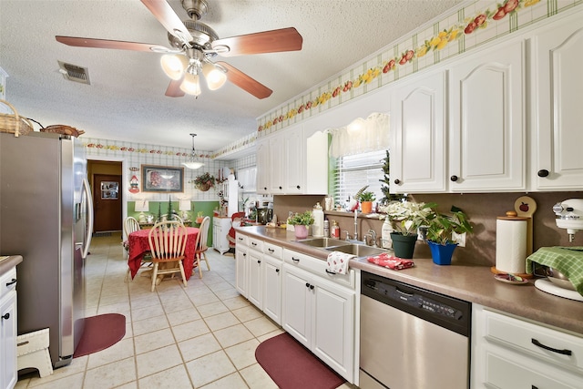 kitchen featuring decorative light fixtures, stainless steel appliances, white cabinets, and sink