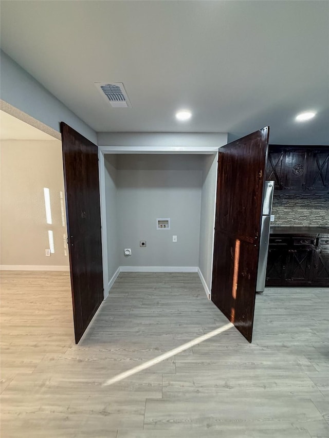 laundry room with visible vents, baseboards, and wood finished floors