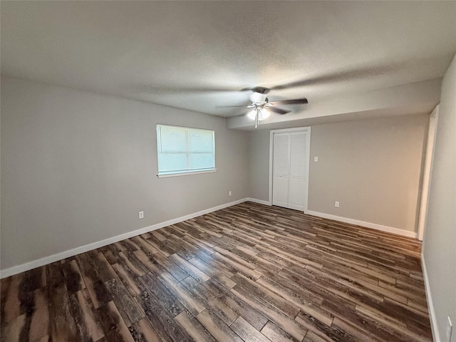 empty room featuring dark wood-style floors, ceiling fan, a textured ceiling, and baseboards