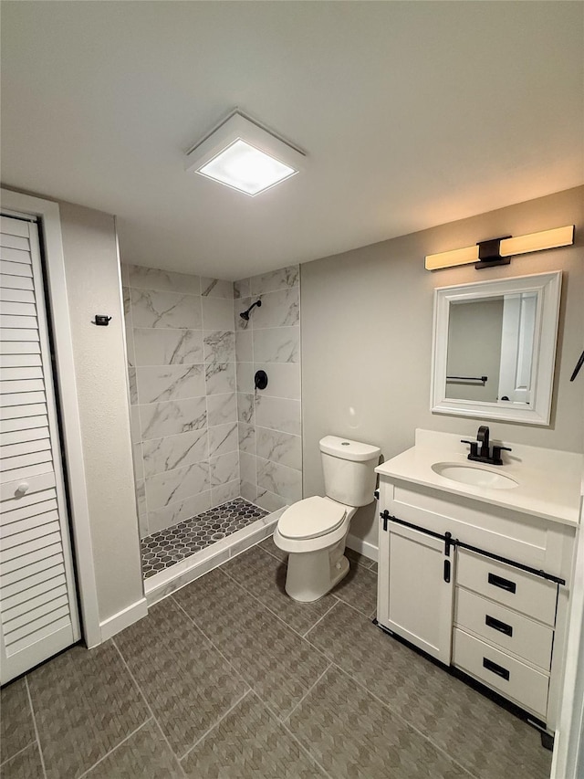 bathroom featuring a shower stall, toilet, vanity, and baseboards