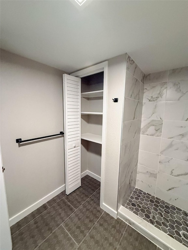 full bathroom with baseboards, a stall shower, and a closet