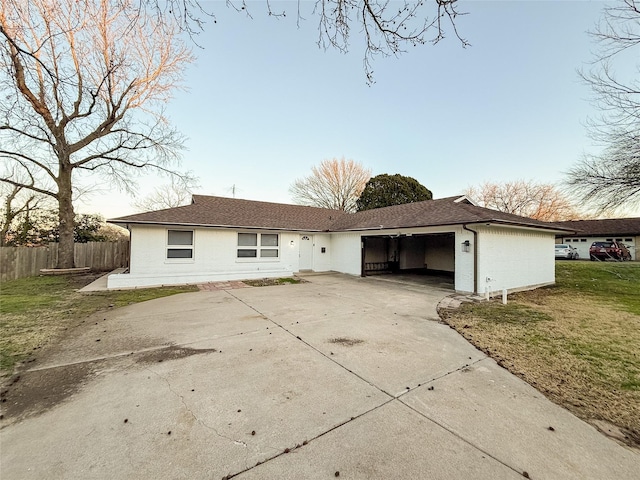 back of house featuring driveway, a shingled roof, a lawn, an attached garage, and fence