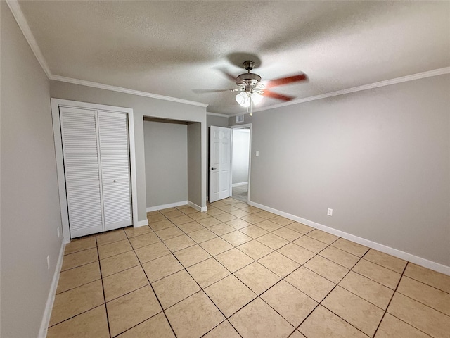 unfurnished bedroom with a textured ceiling, ceiling fan, baseboards, ornamental molding, and two closets