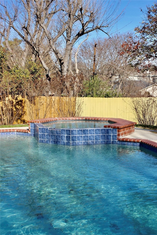 view of pool with a jacuzzi, a fenced in pool, and fence