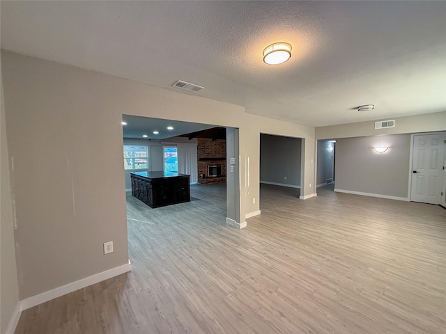 interior space with visible vents, light wood-style flooring, a textured ceiling, and baseboards