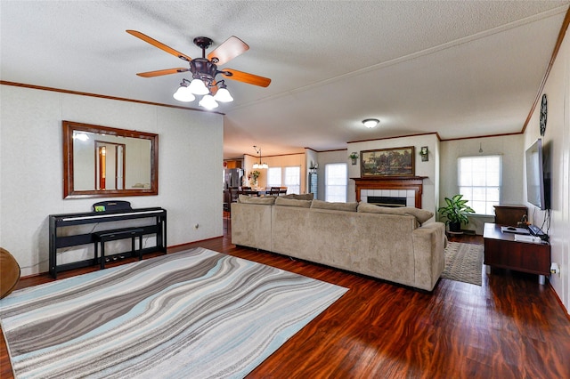 living room featuring a tile fireplace, ceiling fan, crown molding, and dark hardwood / wood-style floors