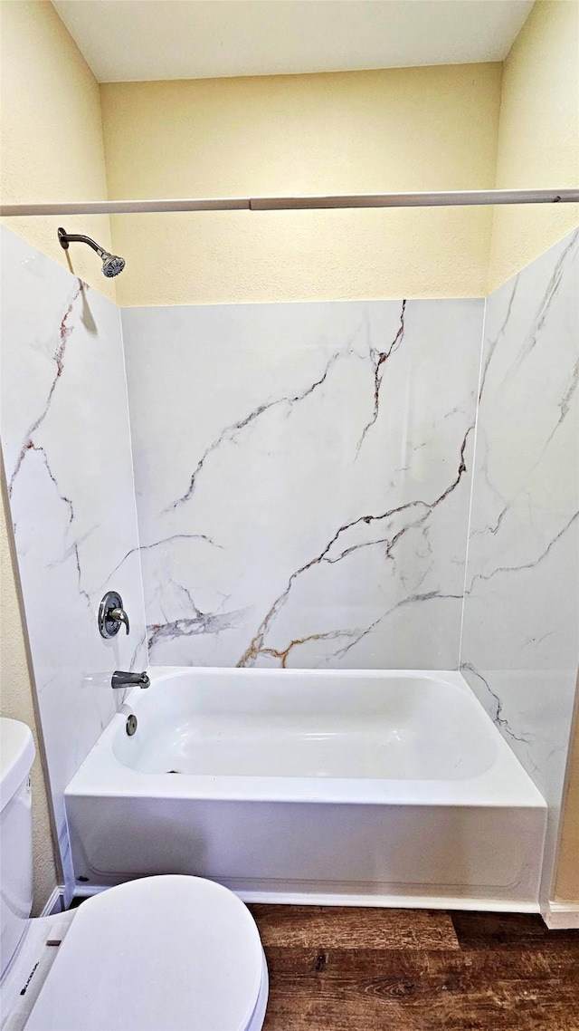 bathroom featuring toilet, shower / washtub combination, and hardwood / wood-style floors