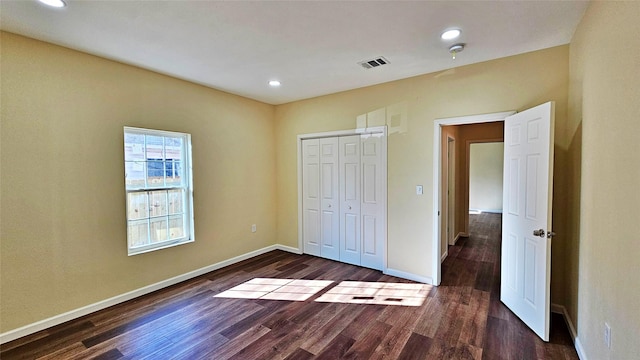 unfurnished bedroom with dark hardwood / wood-style flooring and a closet